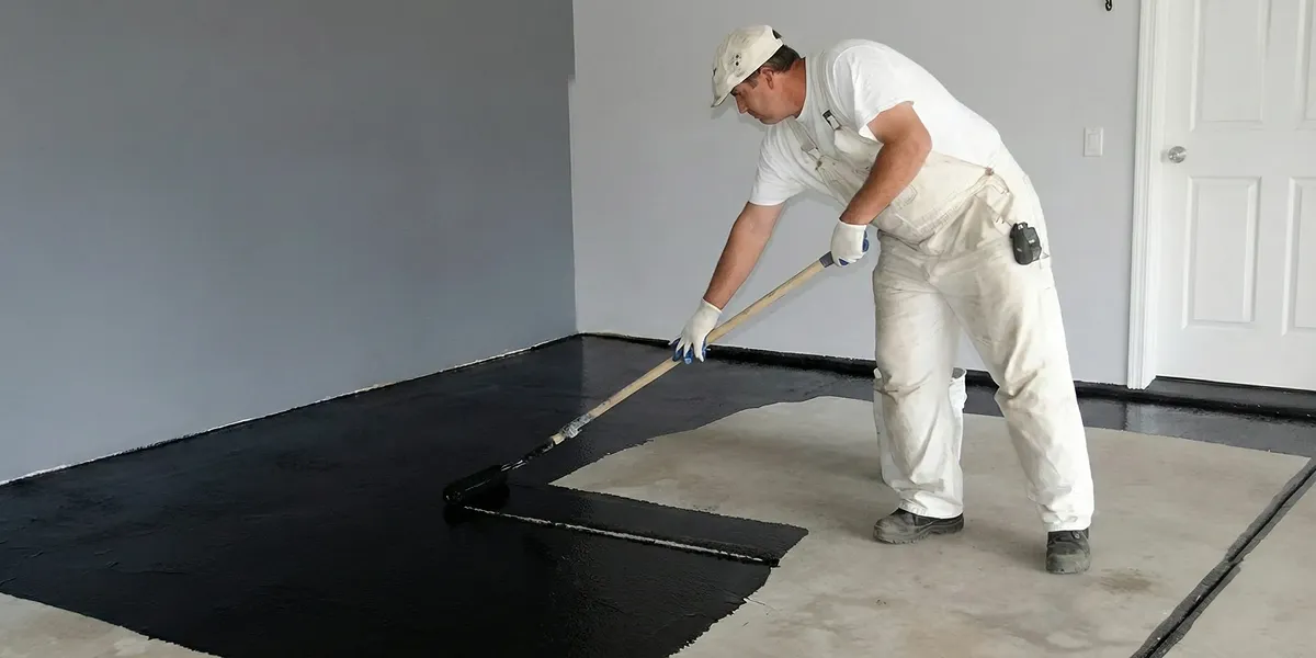 basement waterproofing professional applying waterproof coating to protect a basement floor in Denver, CO